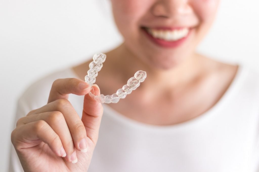smiling woman holding invisalign retainer